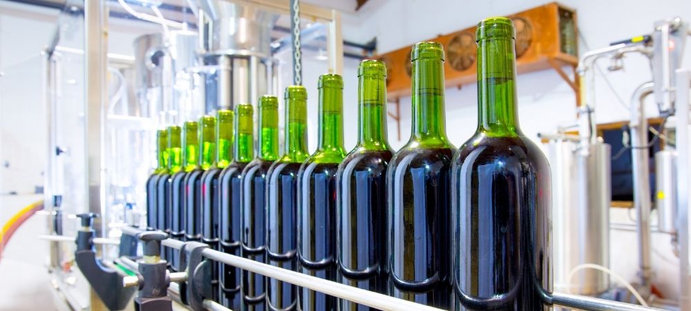 Línea de producción de botellas de vino en una bodega, destacando el control de turbidez en el proceso de embotellado